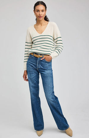 Woman wearing a striped sweater and blue jeans on a plain background