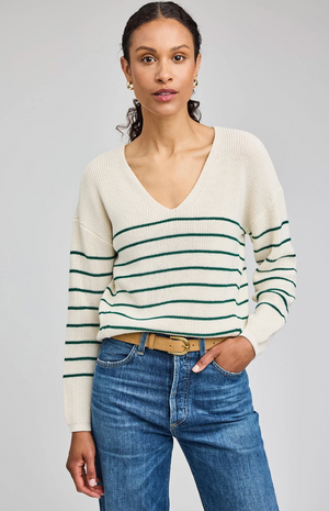 Woman wearing a striped sweater and jeans on a gray background
